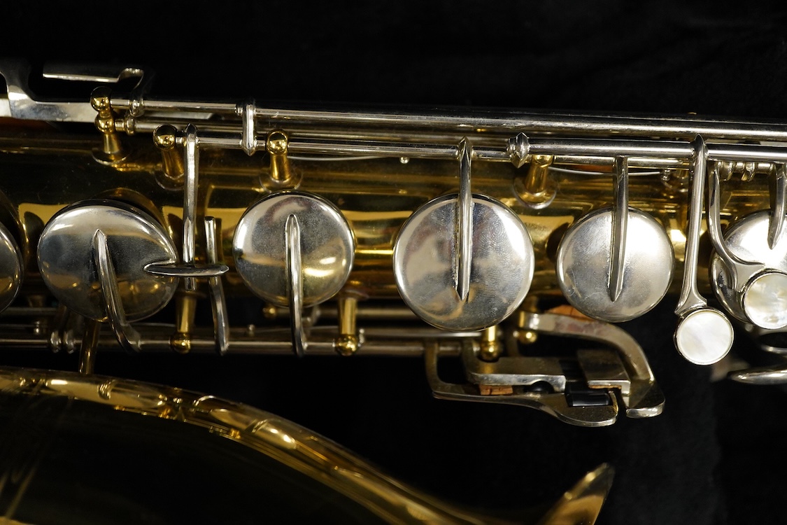 A cased Buescher Aristocrat tenor saxophone and stand